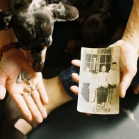 Person sitting with hands out holding a photo and a charm