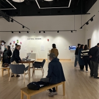 Group of adults of all ages talk and view objects in a museum gallery