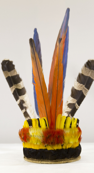 A crown woven with fiber and colorful feathers in red, orange and blue