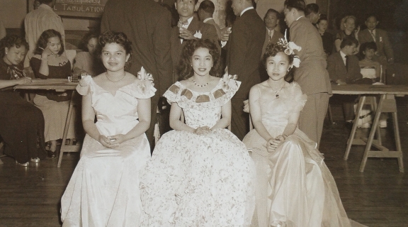 Three young women in celebratory dresses pose for a picture